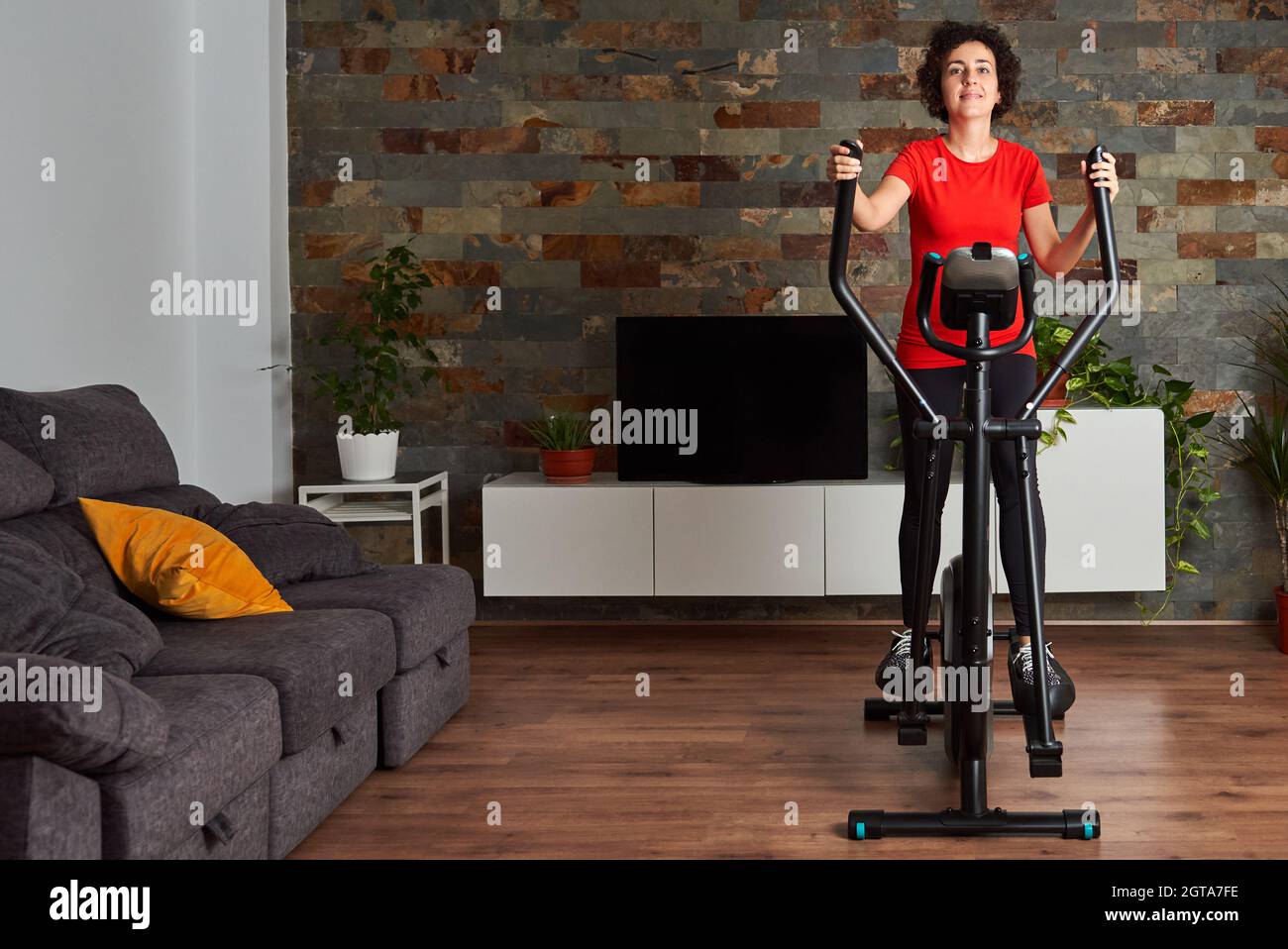 Frau trainiert zu Hause mit einem Crosstrainer Stockfoto