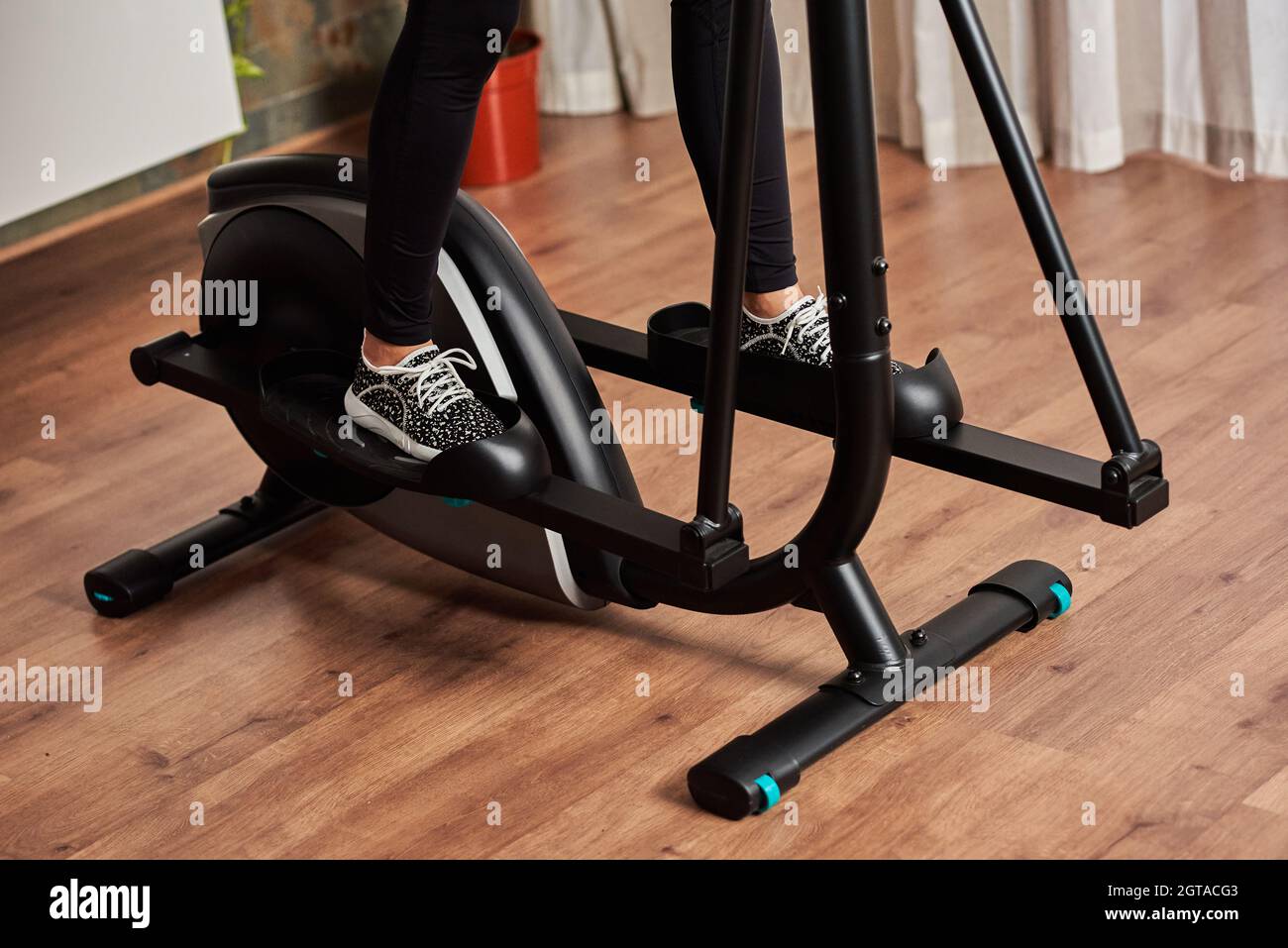 Beine einer Frau, die auf einem Crosstrainer im Wohnzimmer zu Hause  trainiert Stockfotografie - Alamy