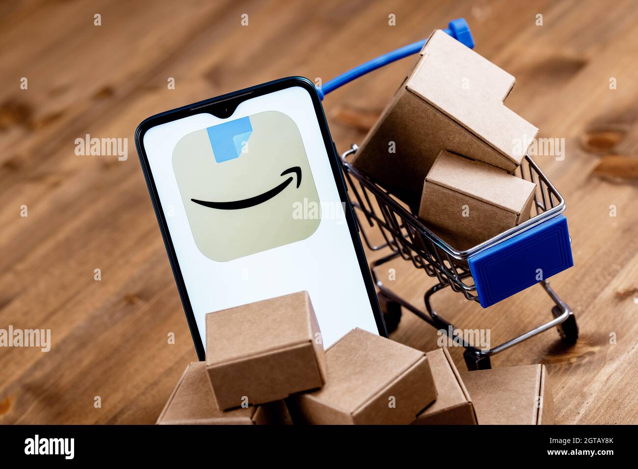 Smartphone mit Amazon App-Logo auf dem Bildschirm, Warenkorb und Paketen. Stockfoto