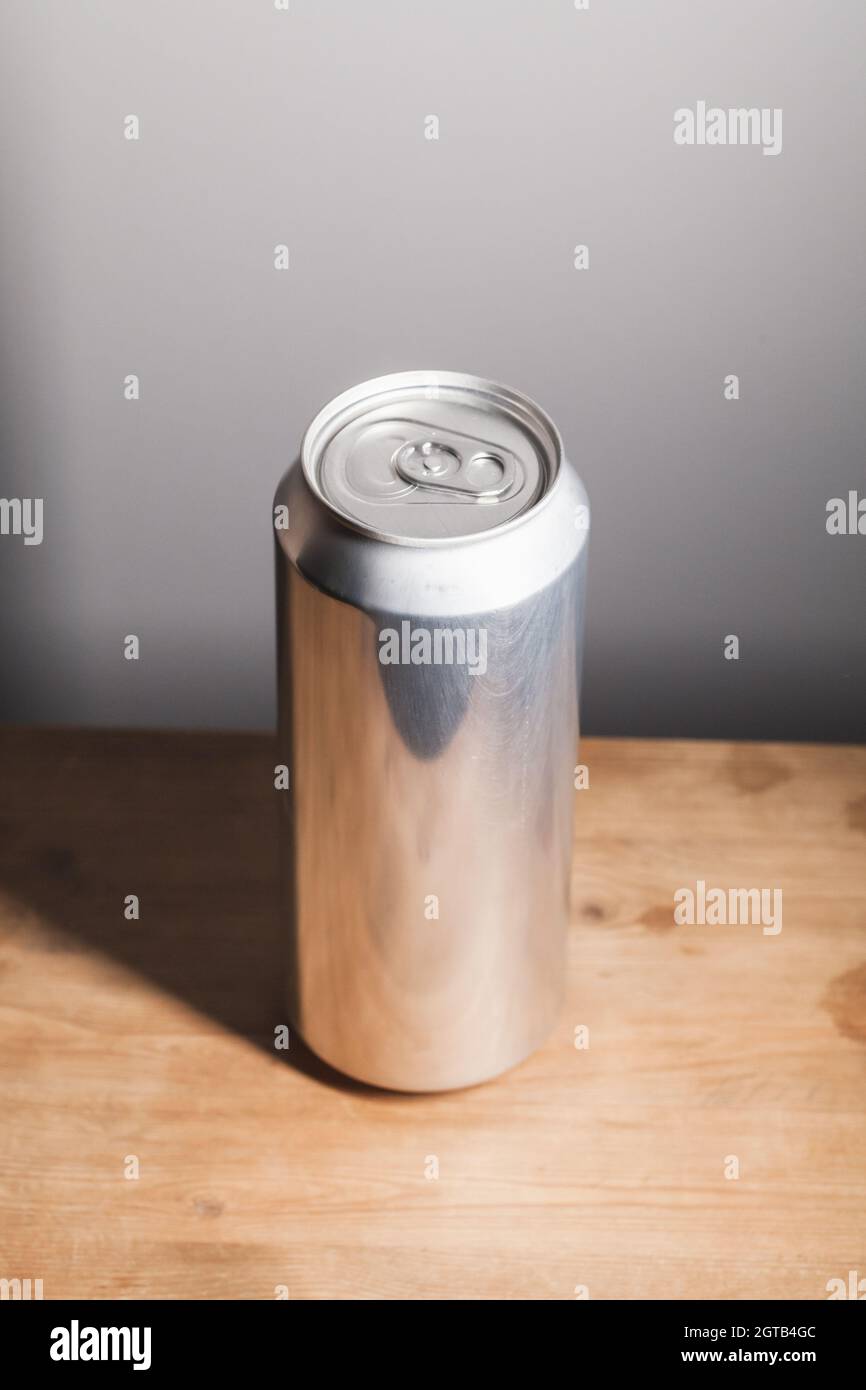 Voll geschlossene, glänzende Aluminiumkiste steht auf einem Holztisch, Standard-Softdrink-Verpackung, vertikales Foto Stockfoto