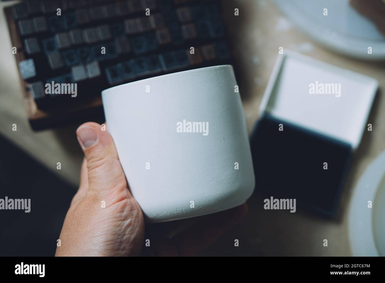 Leere weiße weiße Beton Kerzenglas in der Hand des Künstlers, kreative Malerei und Design bereit Keramik Stockfoto