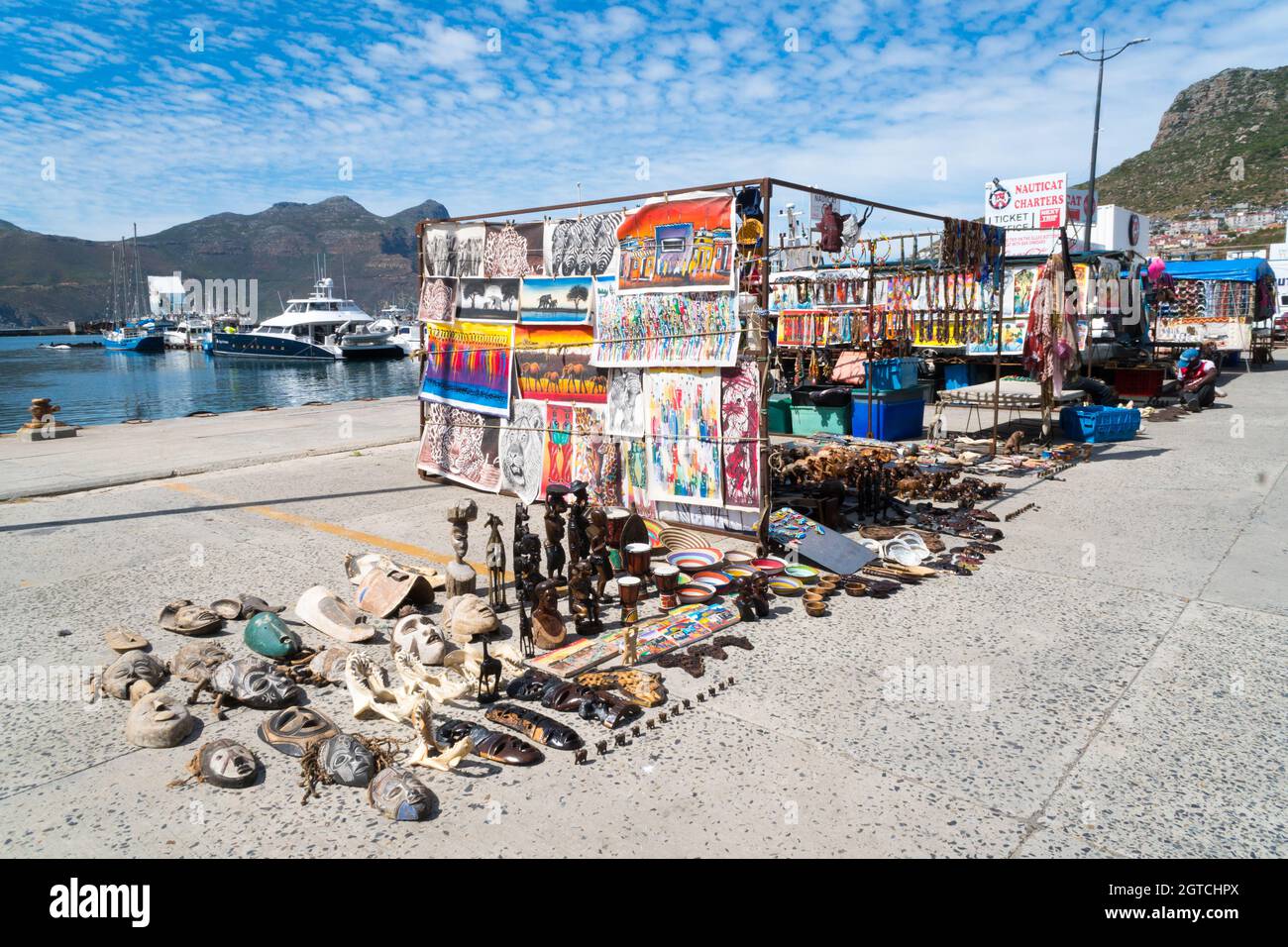 Afrikanische Straßenmarktstände und Händler, die Kuriosen, traditionelle Kunst und Kunsthandwerk sowie Souvenirs im Hafen von Hout Bay verkaufen Stockfoto