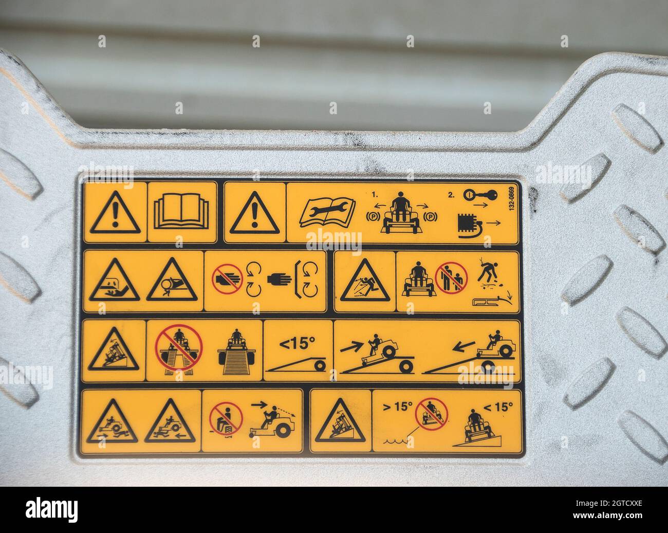 Warnschaltbilder an der Metallfußplatte des neuen Aufsitzmähers. Schematische schwarze Meldungen auf gelbem Hintergrund. Queensland, Australien Stockfoto