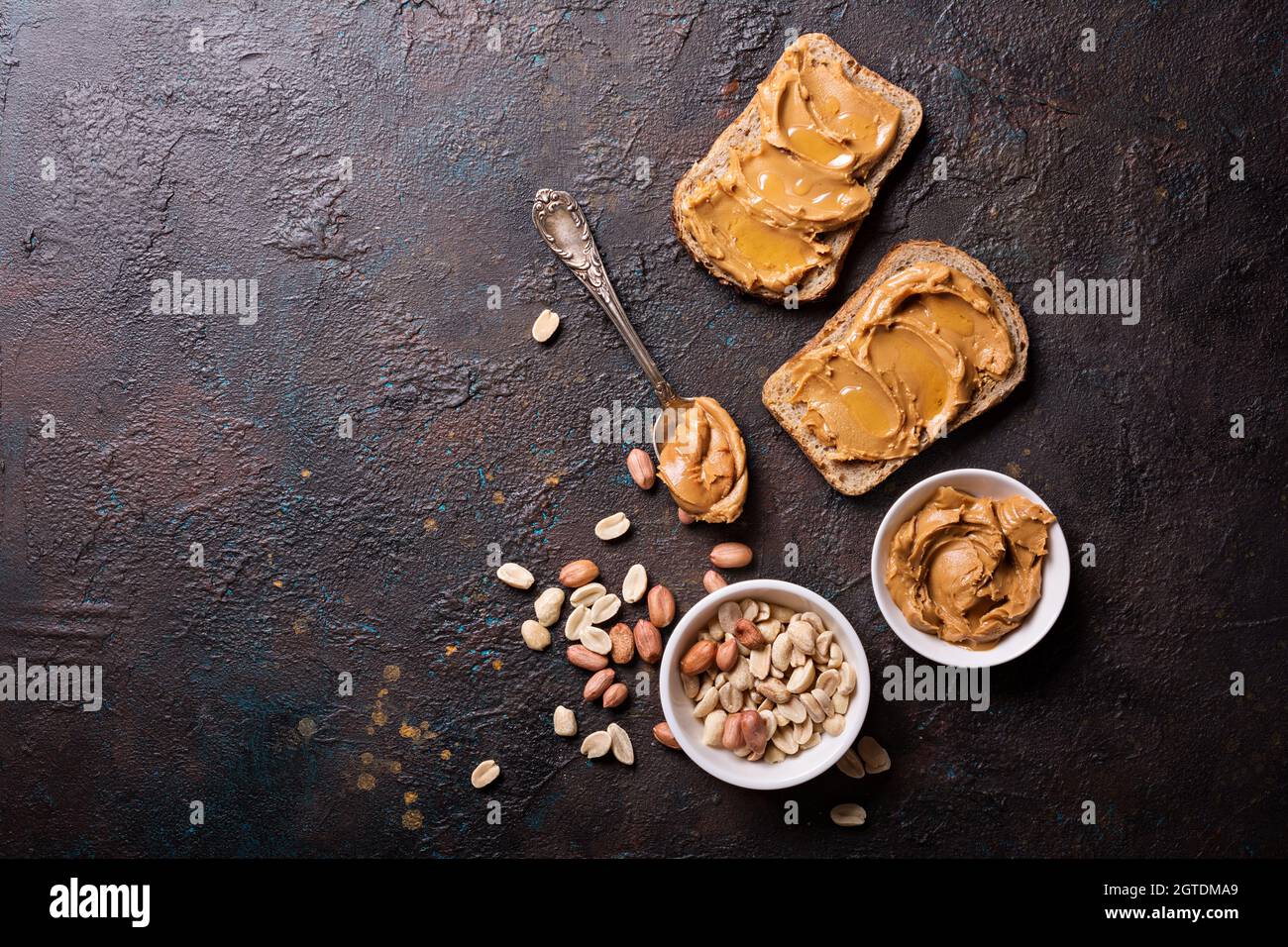 Süsse Erdnusspaste oder Butter mit Honig auf Brot für leckeres Frühstück auf dunklem Betongrund Stockfoto