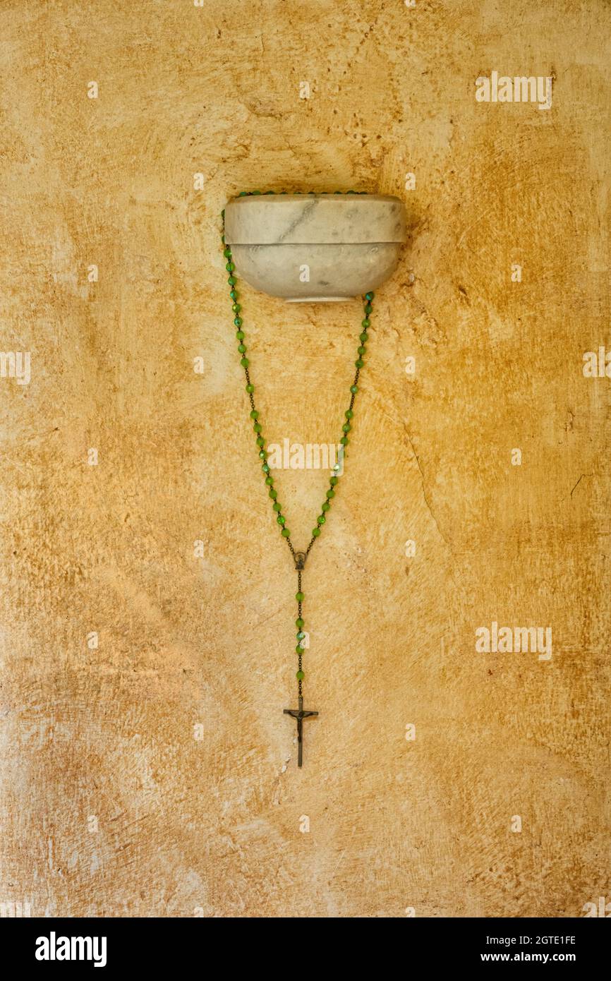 Religiöses Kreuz mit grünen Perlen, die an einer Wand hängen, in der Nähe von Pompei, Italien Stockfoto