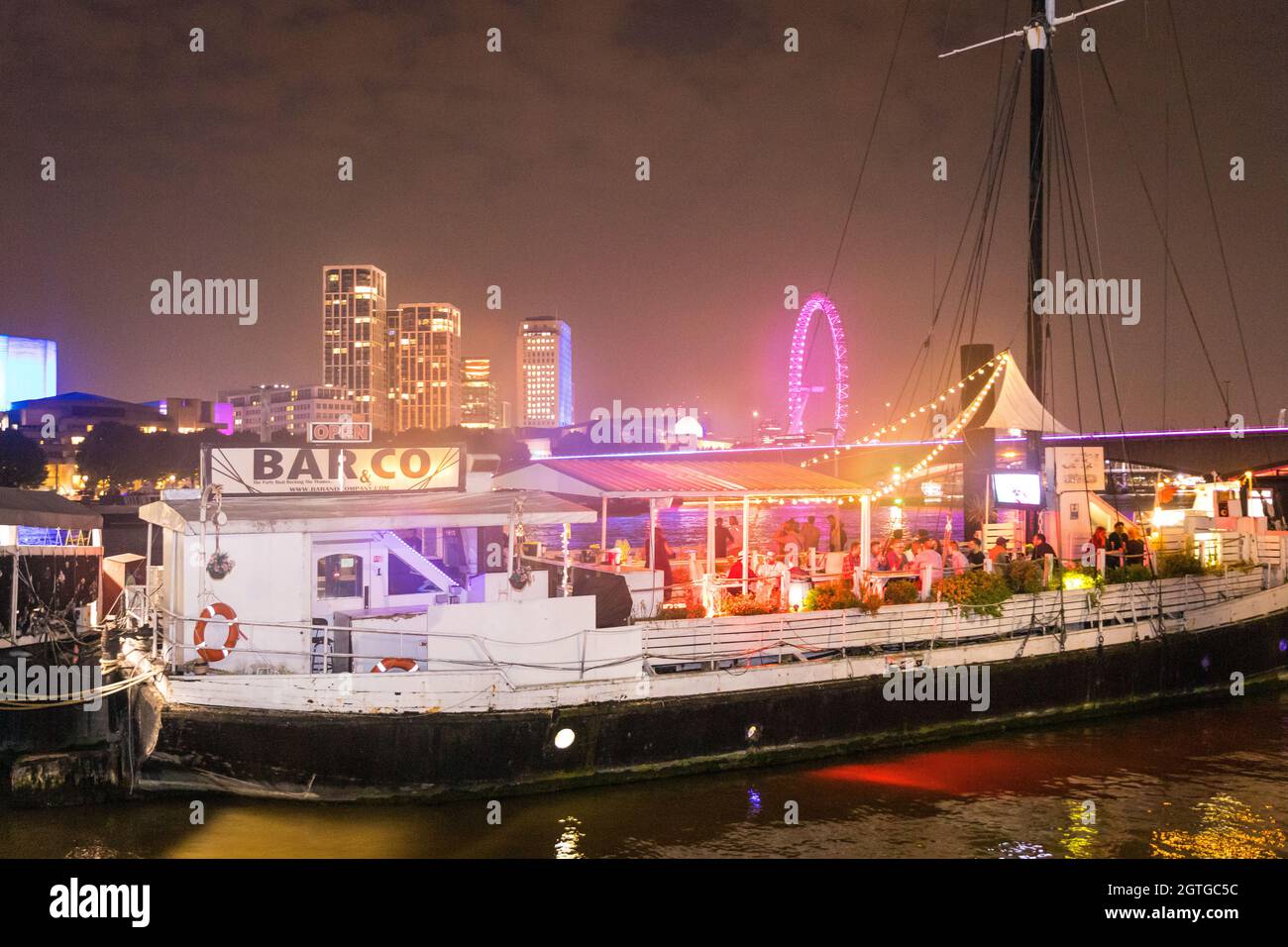 Schwimmende Bar auf der Themse mit southbank bei Nacht im Hintergrund Stockfoto