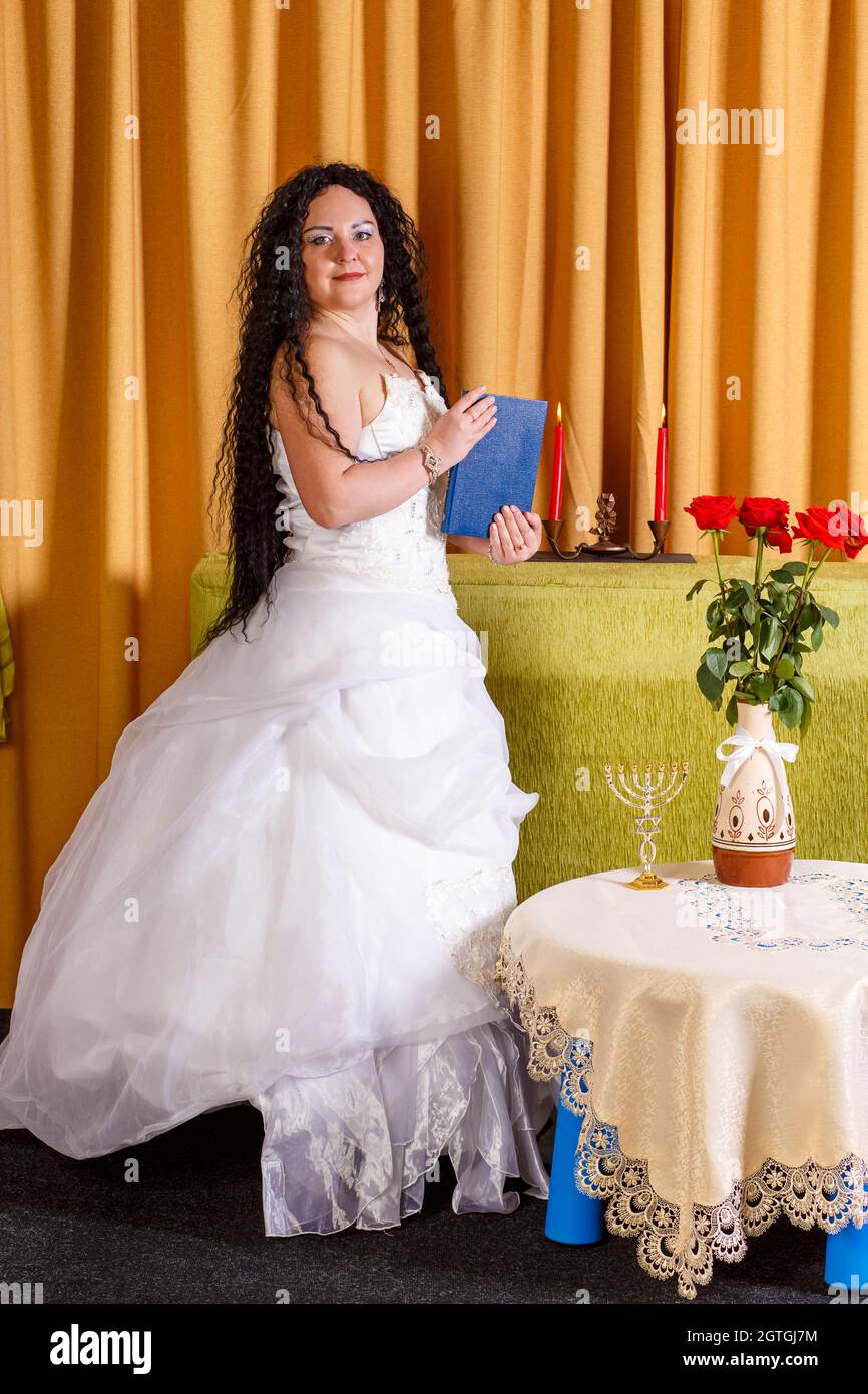 Eine jüdische Braut in Einem weißen Brautkleid ohne Schleier hält Ein  geschlossenes Buch von Tegilim in ihren Händen Stockfotografie - Alamy