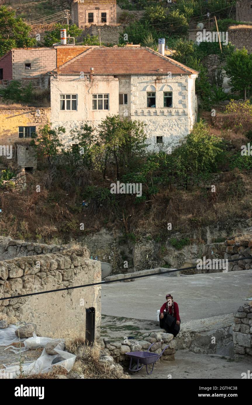 Alltag in einem ländlichen Dorf in der Türkei ein altes weiß getünchtes Haus und eine Frau, die in Zentralanatolien sitzt und wartet Stockfoto