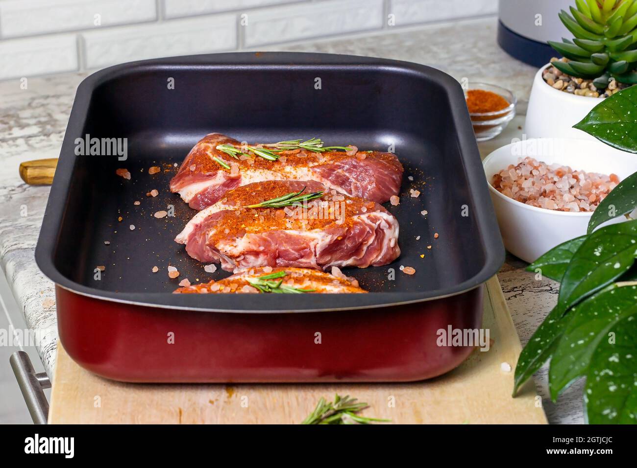 Rohe marmorierte Rindersteak-Scheiben mit Salz und Gewürzen auf einer Backform aus Metall für den Background im Ofen. Die Zubereitung eines frischen Fleisches zum Abendessen. Stockfoto