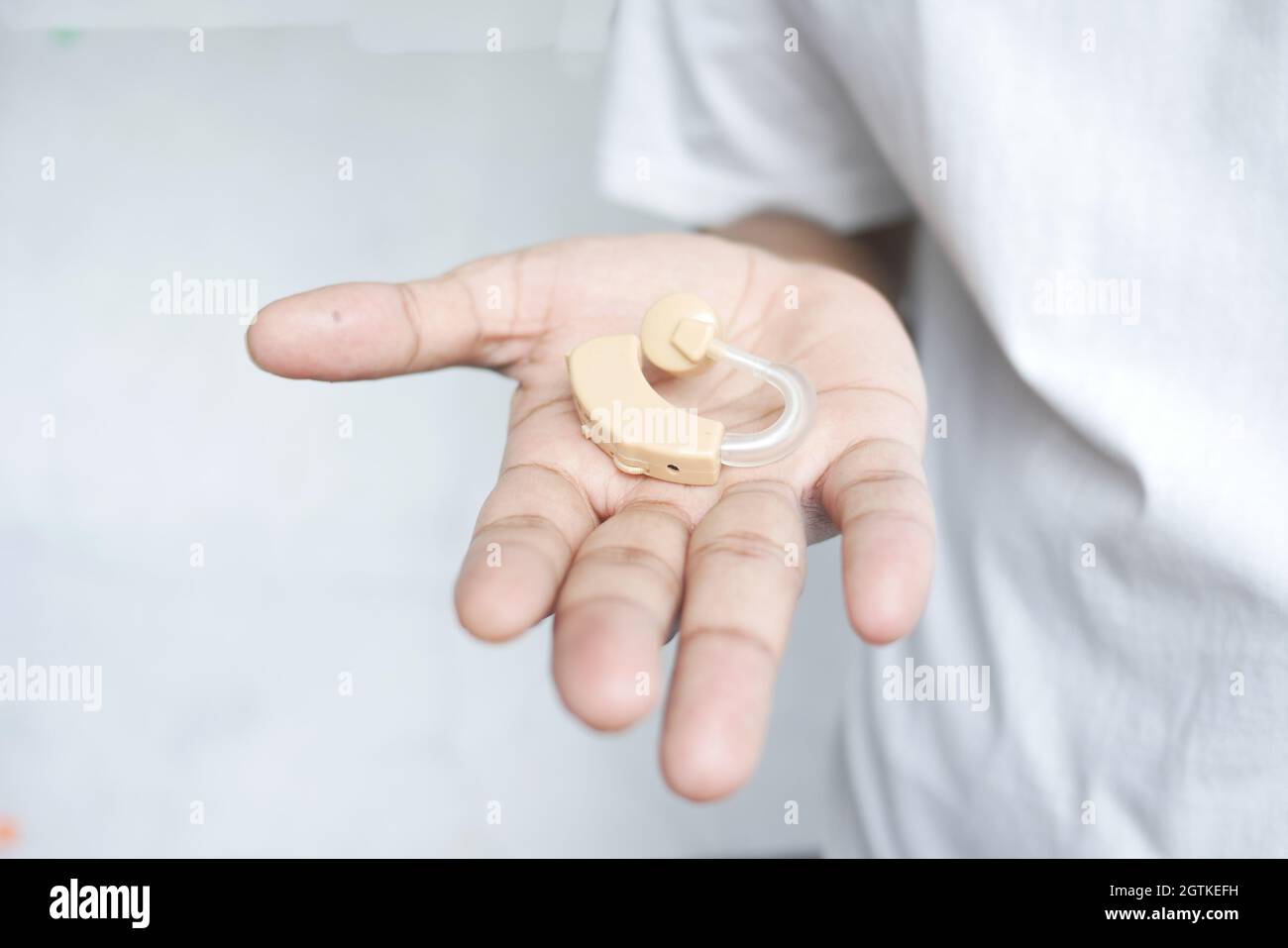 Halten Sie ein Hörgerätetechnik mit der Hand vor weißem Hintergrund Stockfoto