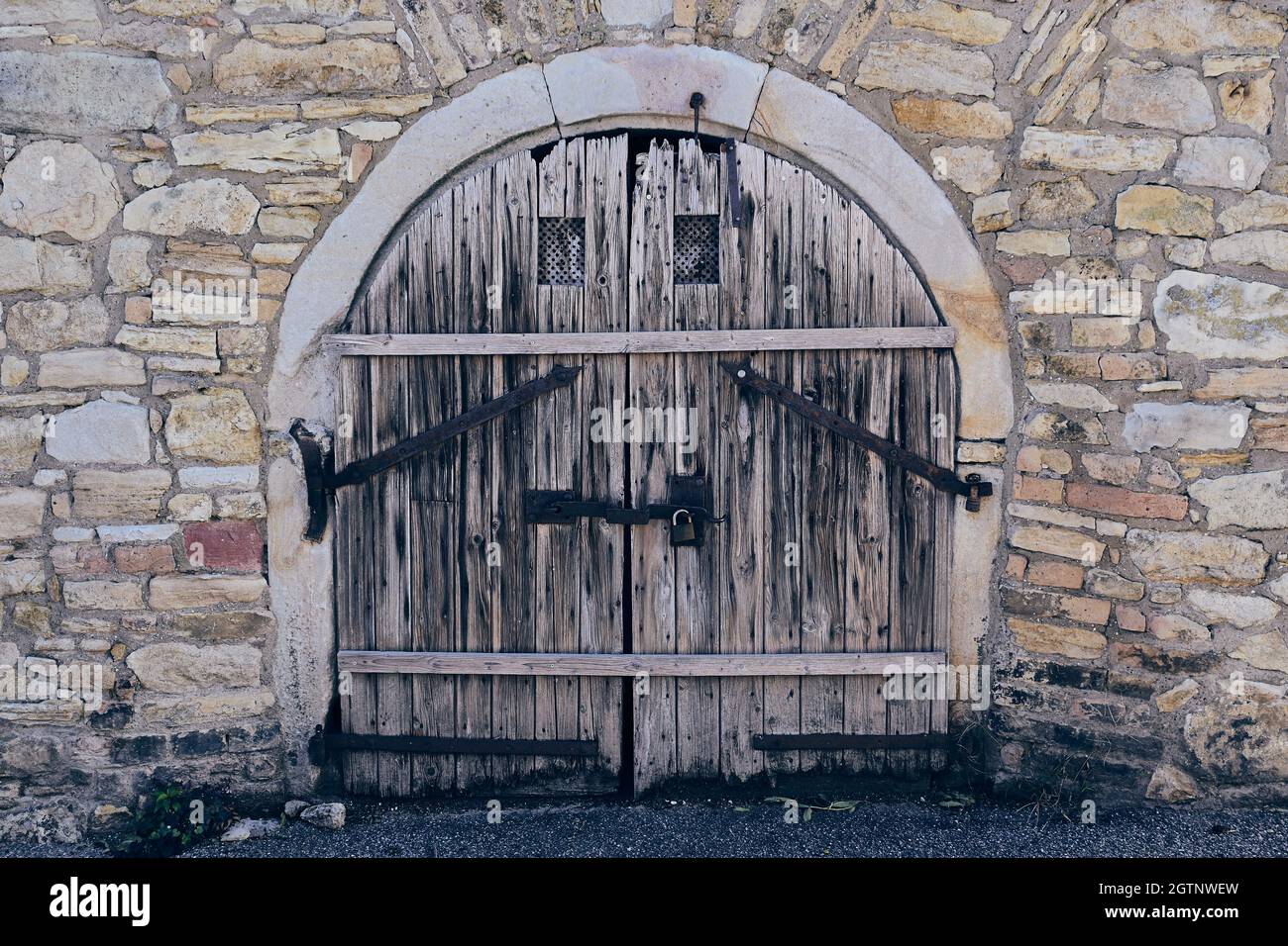Hölzerne Kellertür in einer Steinmauer Stockfoto