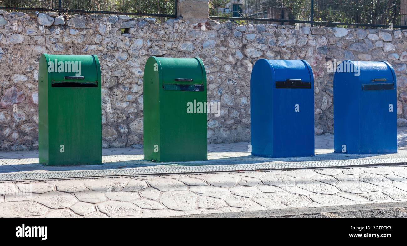 Abfalleimer. Grüne und blaue Mülltonnen in einer Reihe auf dem Bürgersteig der Stadt. Sammeln von recycelbaren Materialien, Recycling, Umweltkonzept Stockfoto