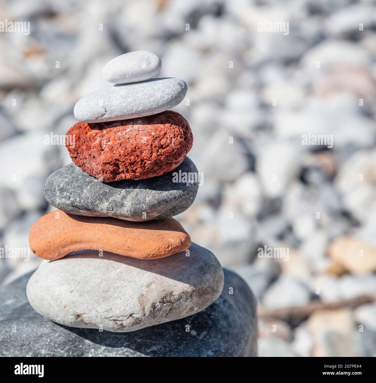 Zen-Balancesteine, glatter Felsturm auf Kiesstrand im Hintergrund, sonniger Tag. Harmonie und Frieden Konzept, Yoga, natürliche Therapie Stockfoto