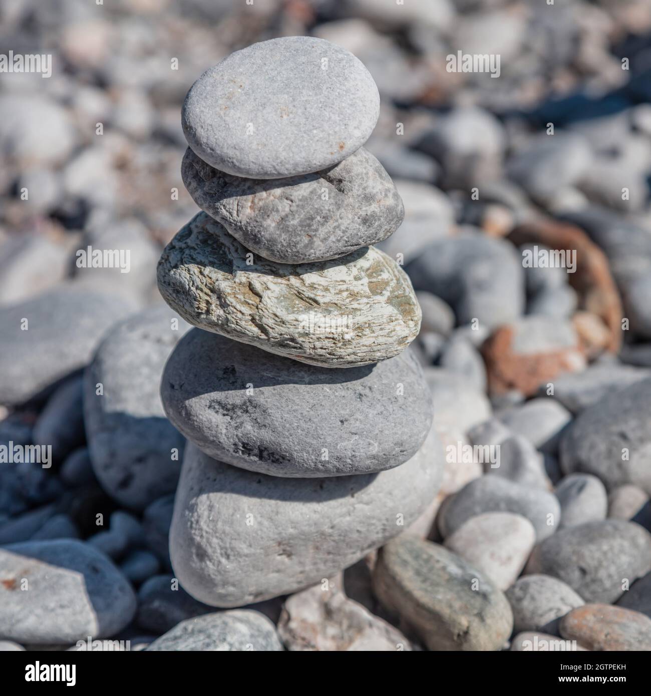 Gleichgewicht, Harmonie und Frieden Konzept. Zen-Steine, glatter Felsturm auf Kiesstrand im Hintergrund, sonniger Tag. Feng Shui, Yoga, natürliche Therapie Stockfoto