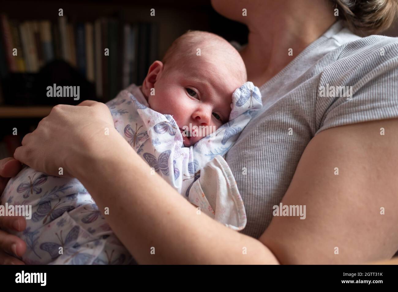 Kaukasische Mutter hält ihr neugeborenes Mädchen, das Zeit miteinander verbringt Stockfoto