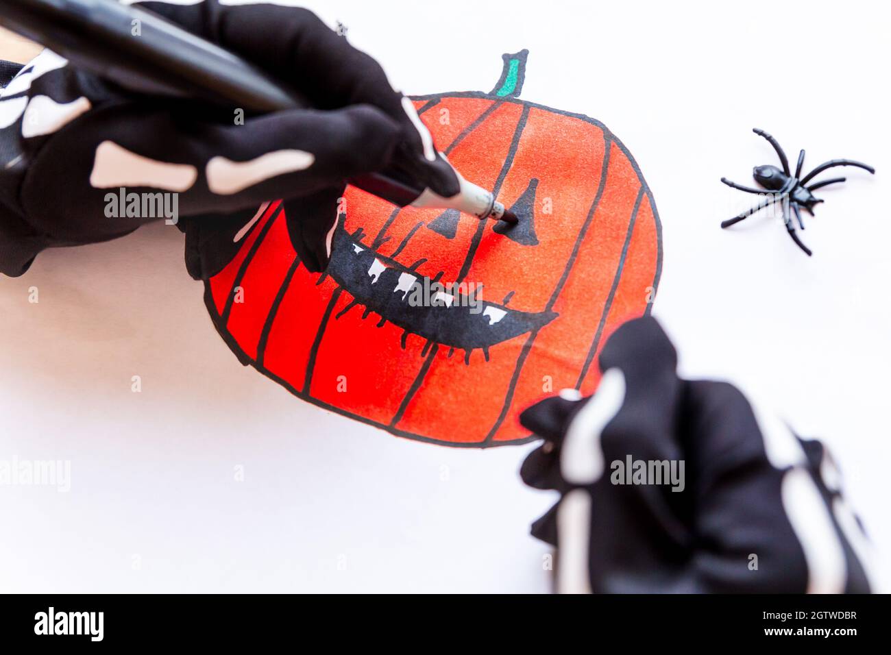 Hände zeichnen einen toothy Kürbis für Halloween, Nahaufnahme. Skizze eines orange lachenden Kürbisses mit scharfen Zähnen. Mach dich bereit für die Party. Jack Stockfoto