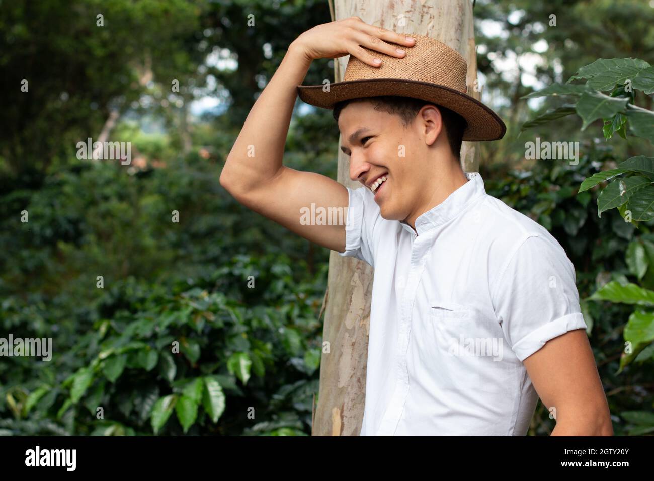 Bauer in Kaffeeplantage mit Hut lächelnd. Farmbesitzer beobachtet seine Kaffeekulturen. Kaffeebauer auf den Feldern. Stockfoto