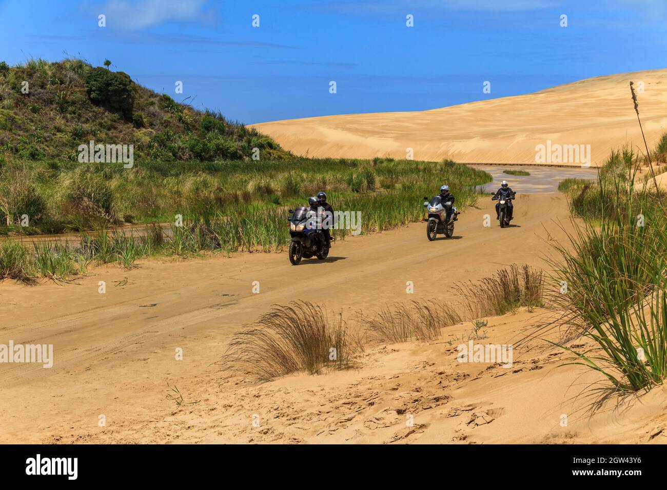 Eine Gruppe von Menschen auf Motorrädern, die durch die riesigen Sanddünen von Te Paki in Northland, Neuseeland, reisen Stockfoto