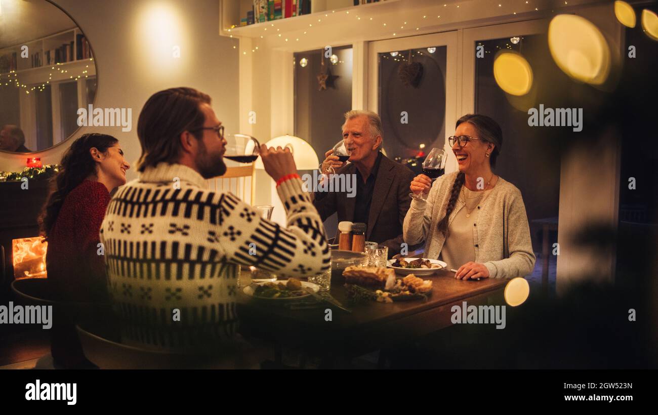 Europäische Familie sitzt am Esstisch und trinkt Wein. Familie, die zu Hause ein Danksagessen hatte. Stockfoto