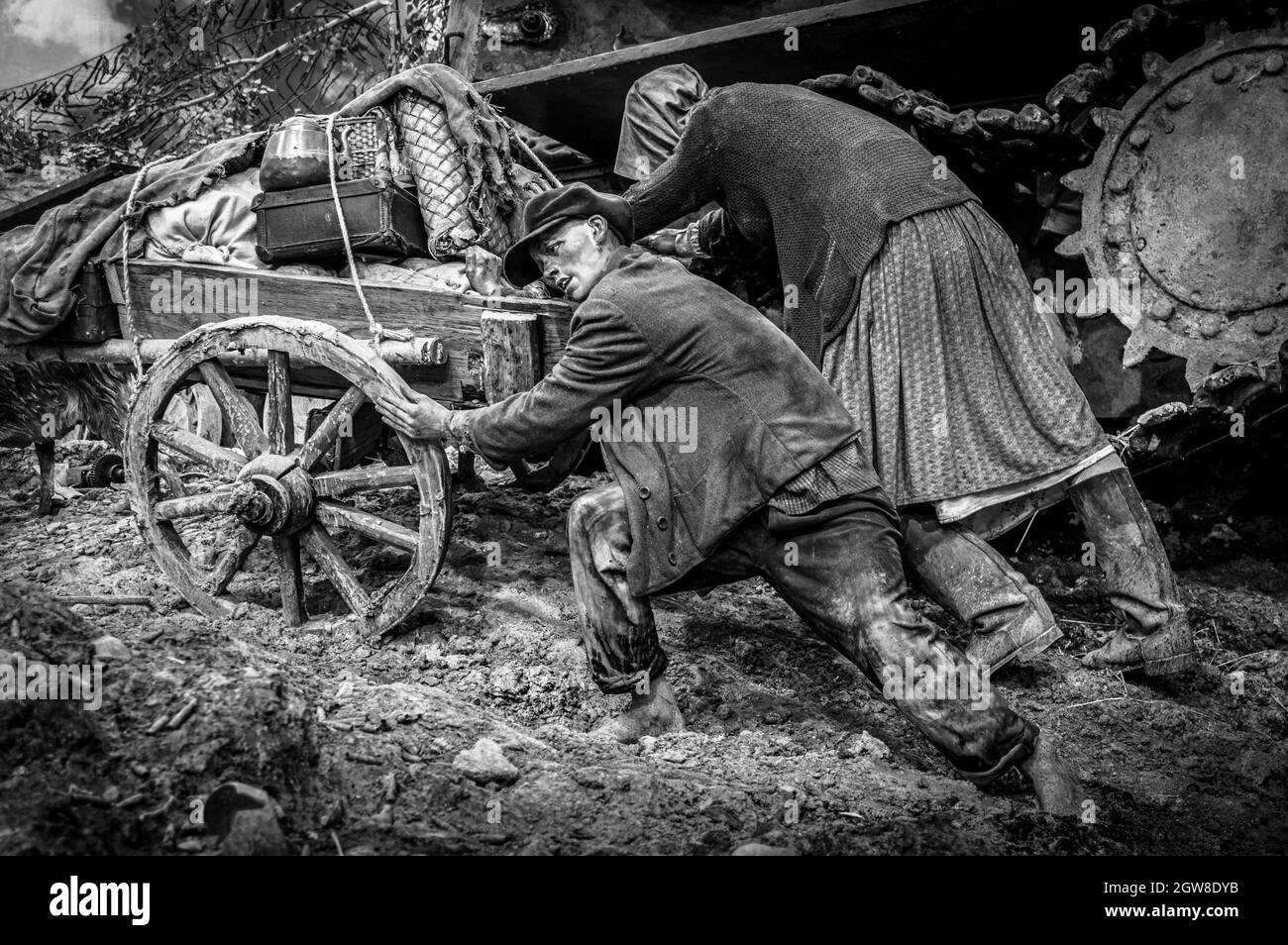 Verheiratetes Paar, das den Wagen voller Habseligkeiten schiebt. Historisches Diorama des Zweiten Weltkriegs mit dem Titel „Memory Speaks. A Way Through the war“. Schwarz und Weiß. Stockfoto