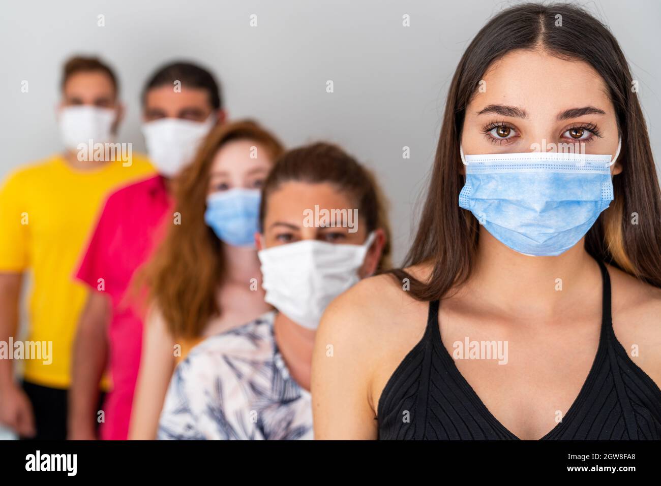 Gruppe von Menschen in der Schlange mit schützenden Gesichtsmaske in sozialer Distanz warten. Pandemie und Gesundheitsversorgung Konzept. Hochwertige Fotos Stockfoto