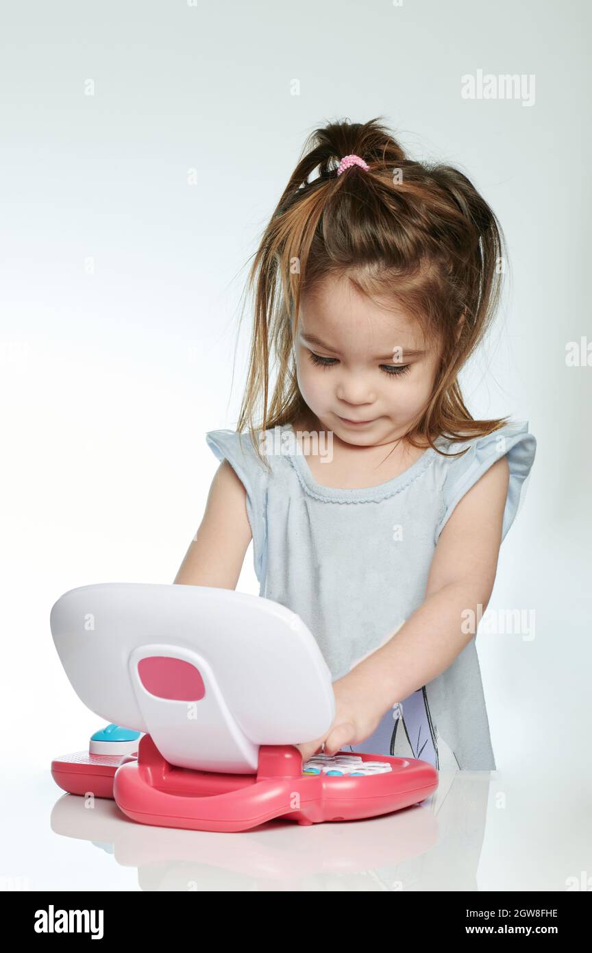 Fröhliches Baby Mädchen lernen verwenden Laptop isoliert auf weißem Studio Hintergrund Stockfoto