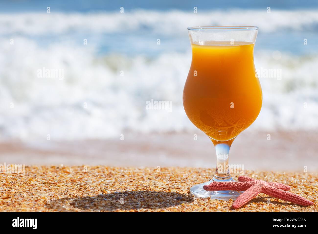 Ein Glas Mangosaft und Seesterne am Strand Stockfoto