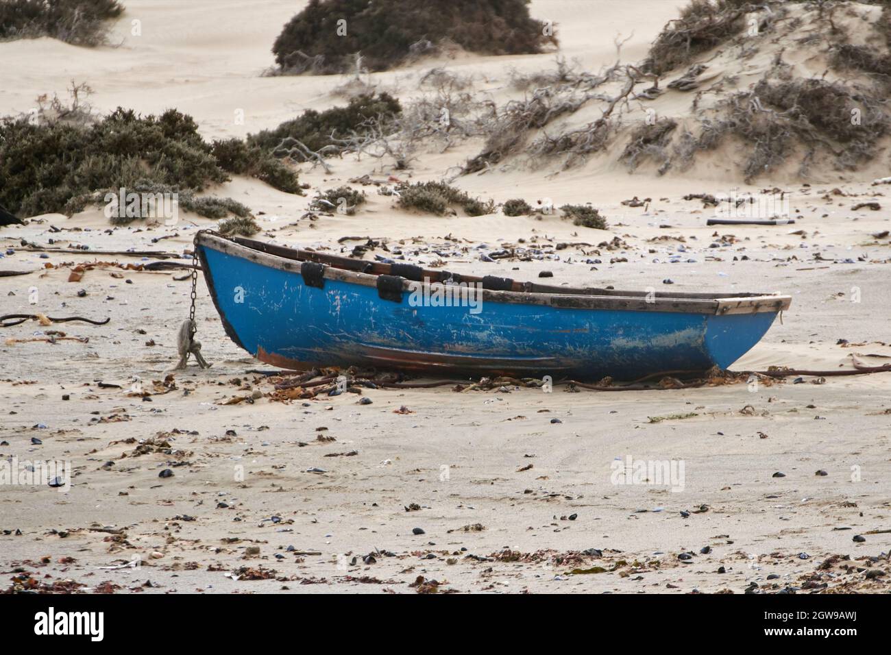 Einfaches Fischerboot aus Holz, das mit einer Kette am Strand befestigt ist. Stockfoto