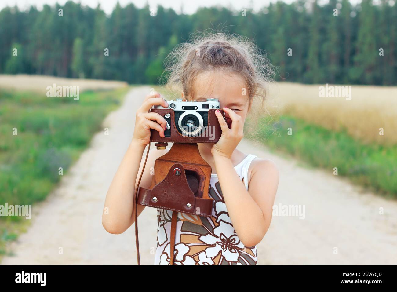 Happy schöne kleine Mädchen im Retro-Outfit ist die Aufnahme von Bildern mit alten Filmkamera. Stockfoto