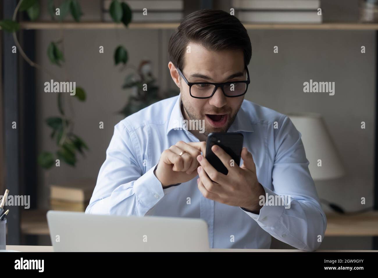 Überglücklich Mann in der Brille lesen gute Nachrichten in der Nachricht Stockfoto