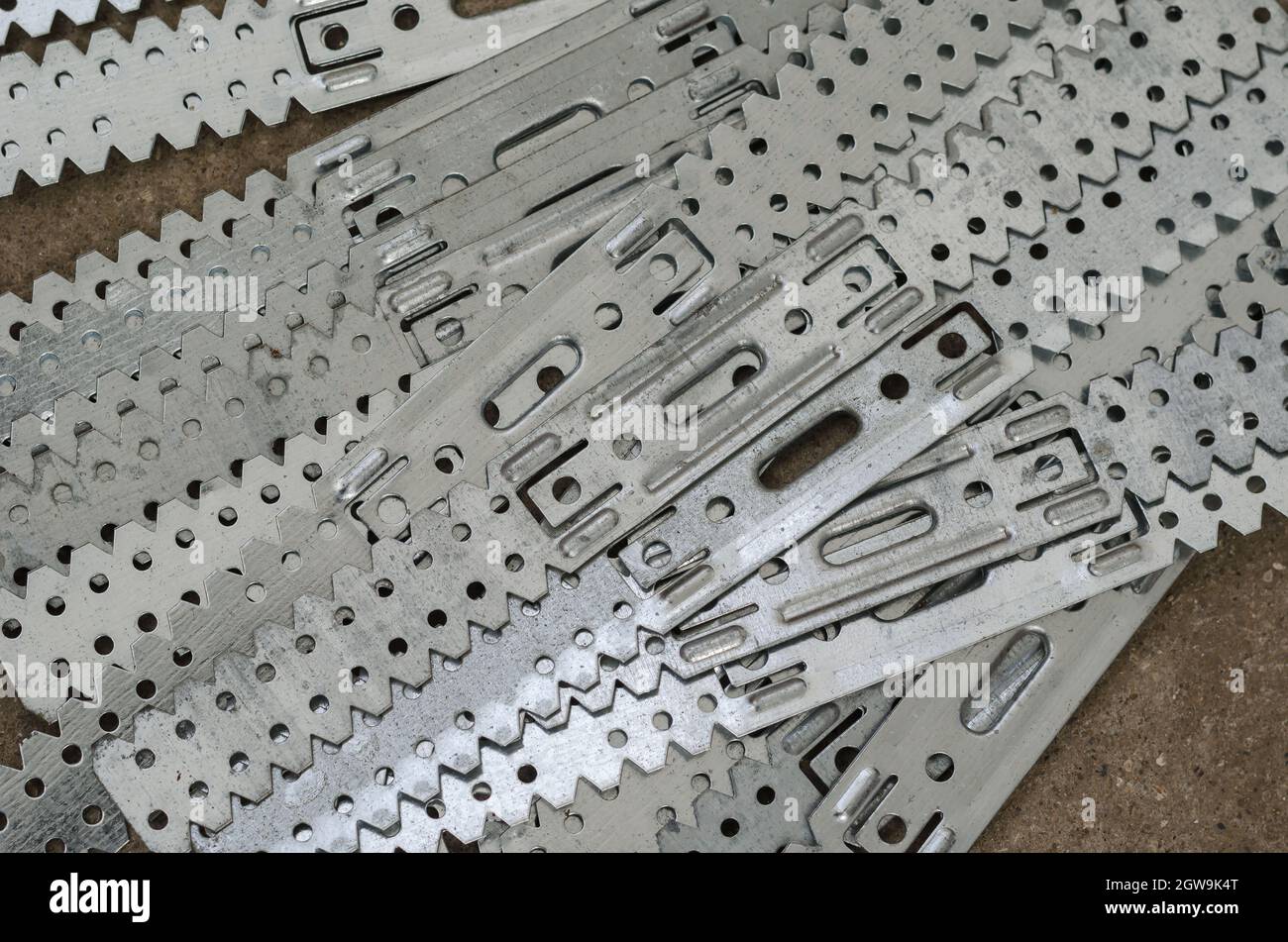Gerader Aufhänger für Gipskarton. Trockenbauhalterungen. Gruppe von langen perforierten verzinkten Stahlplatten. Im Raum. Selektiver Fokus. Stockfoto