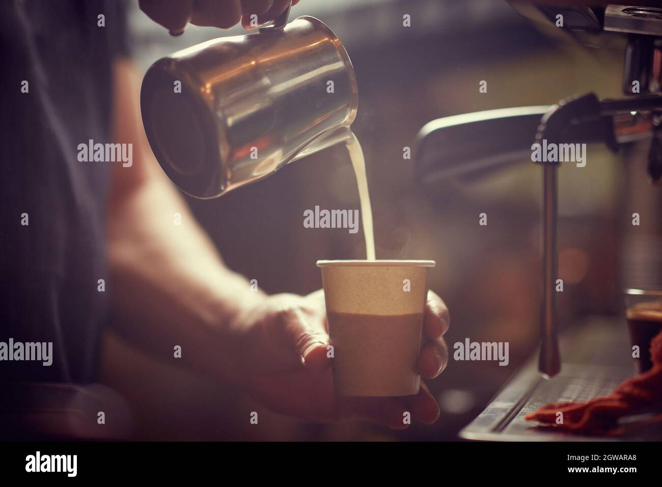 Gieße Milch in die Tasse für frischen Kaffee. Stockfoto