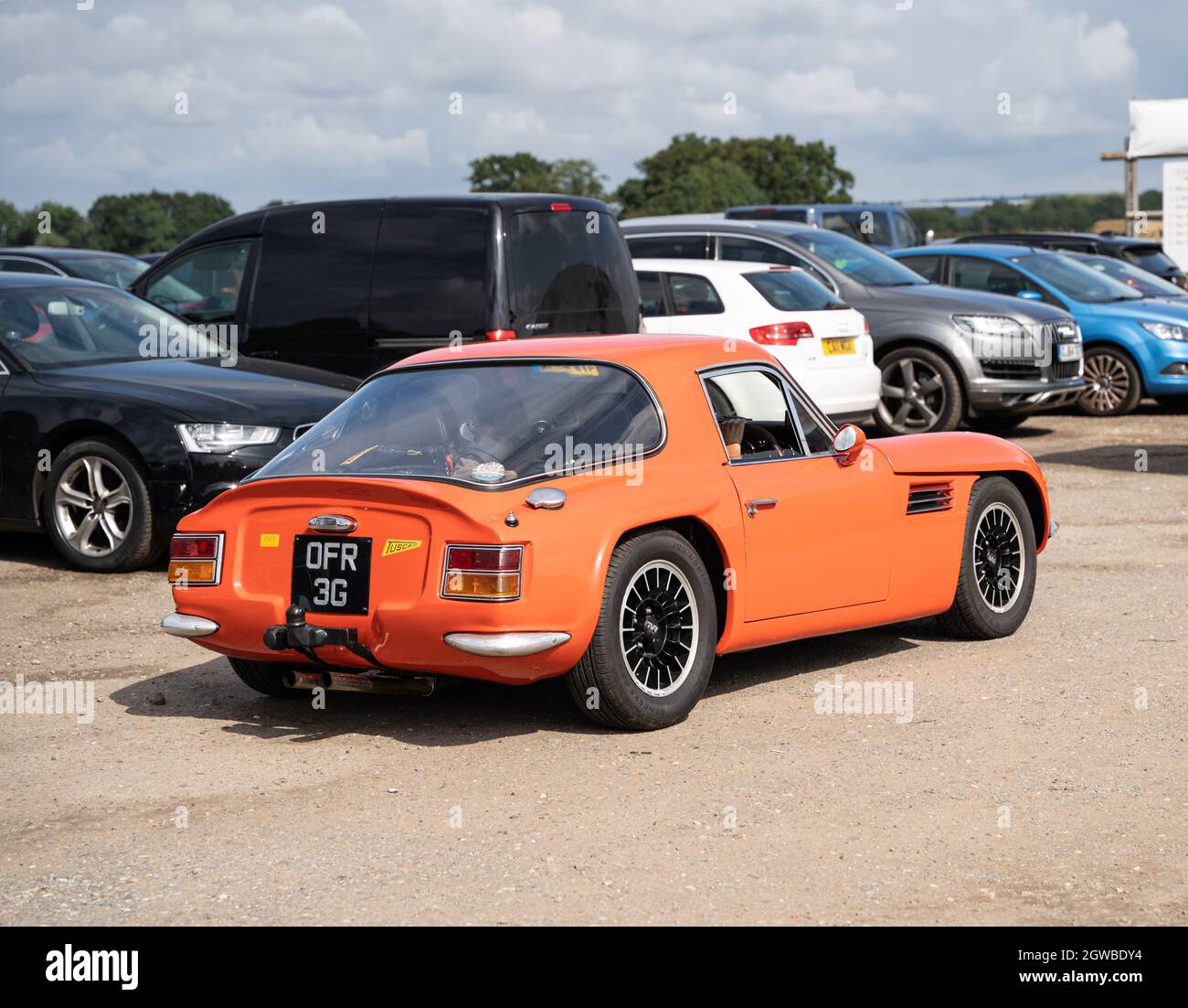 Klassischer orangefarbener TVR-Sportwagen auf dem Parkplatz mit modernen Fahrzeugen Stockfoto