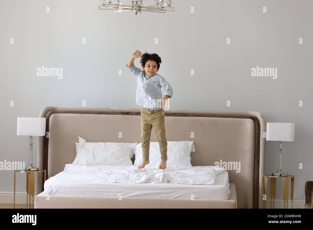 Fröhlicher kleiner Junge, der auf dem Bett springt. Stockfoto