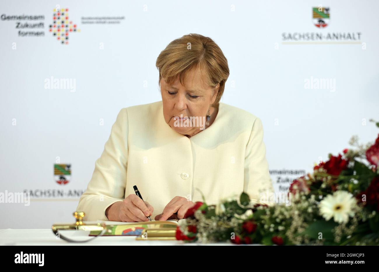 Die scheidende Bundeskanzlerin Angela Merkel unterzeichnet im Goldenen Buch  der Stadt vor Beginn einer Zeremonie im Rahmen der Feierlichkeiten zum 31.  Jahrestag des deutschen Vereinigungstages in Halle, Deutschland, am 3.  Oktober 2021.