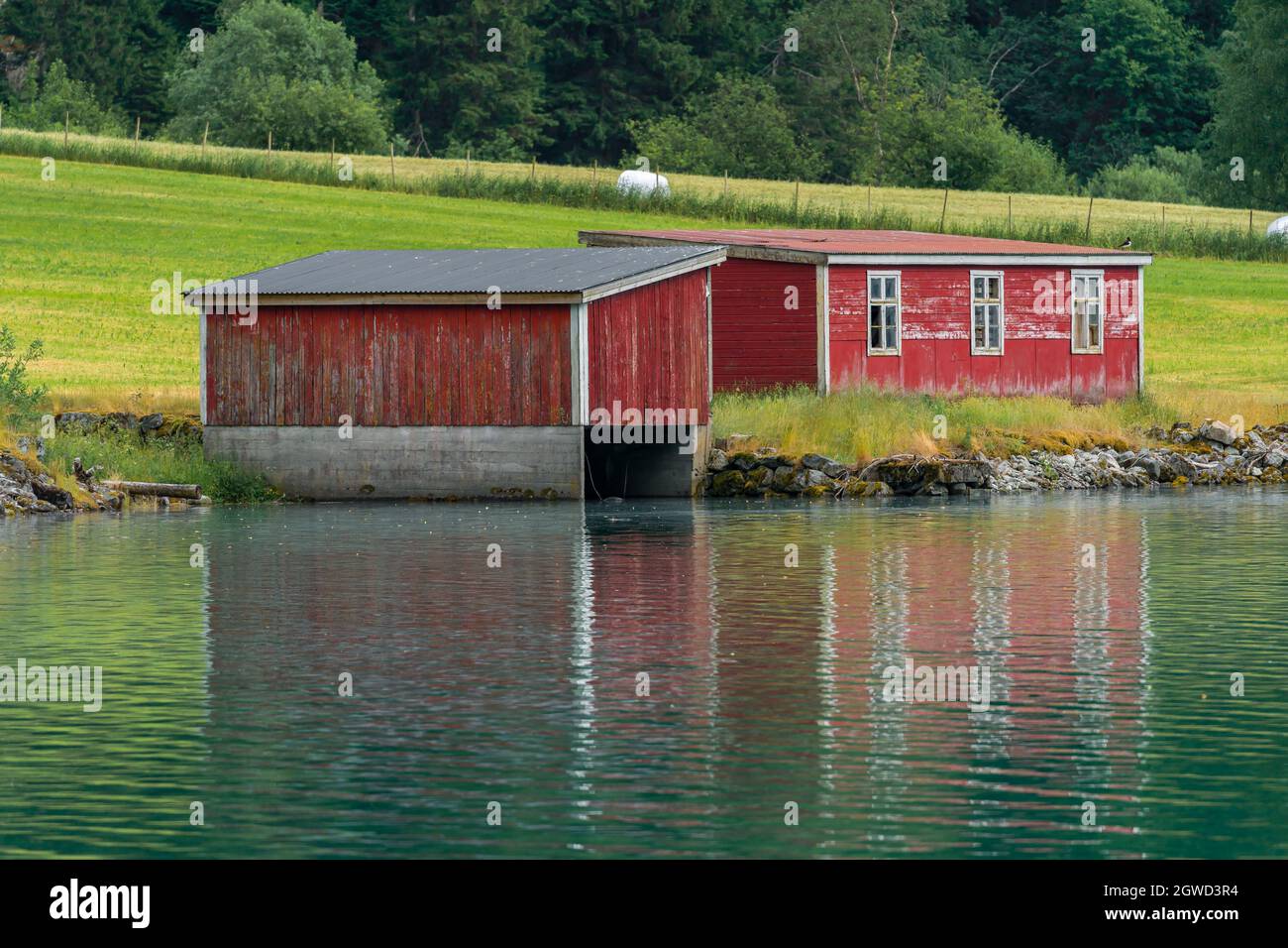 LOEN, NORWEGEN - 2020. JUNI 20. Grüner See und ein rotes Bootshaus. Stockfoto