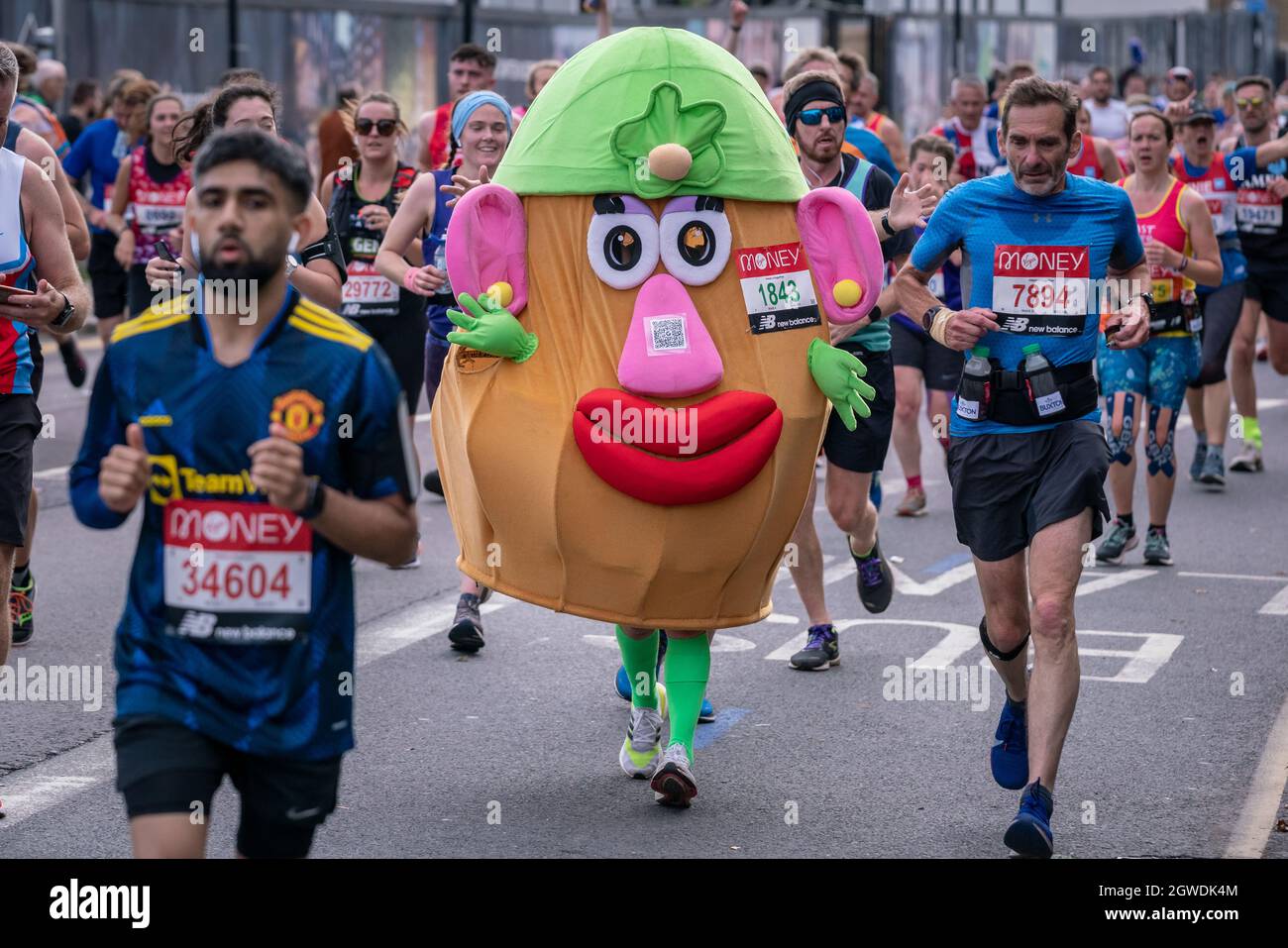 London, Großbritannien. Oktober 2021. Herr Potato Head Runner. Der London Marathon passiert die Evelyn Street im Südosten Londons, die 8-Meilen-Marke der 26.2-Meilen-Strecke von Deptford, auf der die Läufer von den Anwohnern begrüßt und bejubelt werden. Es wird erwartet, dass bis zu 40,000 Rennen laufen werden, wobei Tausende praktisch an dem vielleicht größten Rennen der Geschichte teilnehmen werden. Die Veranstaltung, die sich nun in ihrem fünften Jahrzehnt befindet, hat seit ihrer ersten Veranstaltung im Jahr 1981 mehr als 1 Mrd. £für Wohltätigkeitsorganisationen aufgestockt. Kredit: Guy Corbishley/Alamy Live Nachrichten Stockfoto