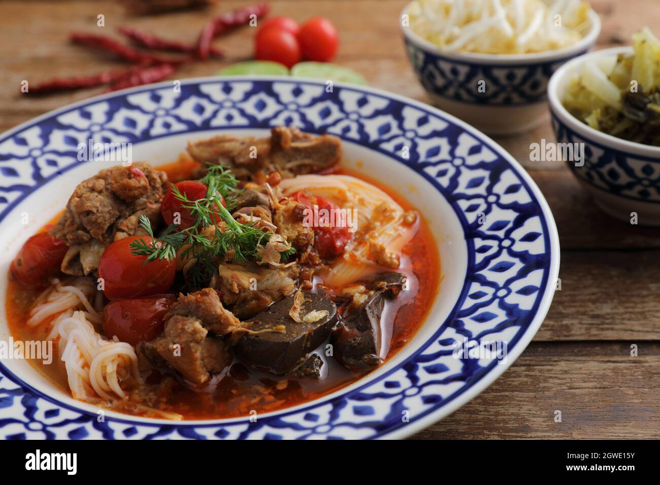 Lokale nordthailändische Küche Reisnudeln mit Schweinefleisch in würzigen Suppe im Holzhintergrund Stockfoto