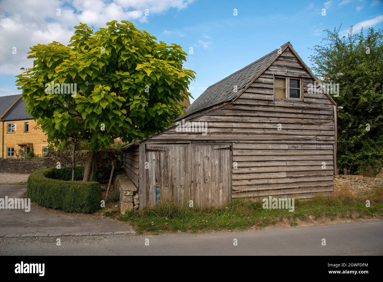 Guiting Power, Gloucestershire, England, Großbritannien. 2021. Eine alte Holzscheune mit kleinen Garagentoren im ländlichen Cotswolds-Dorf Guiting Power. Stockfoto