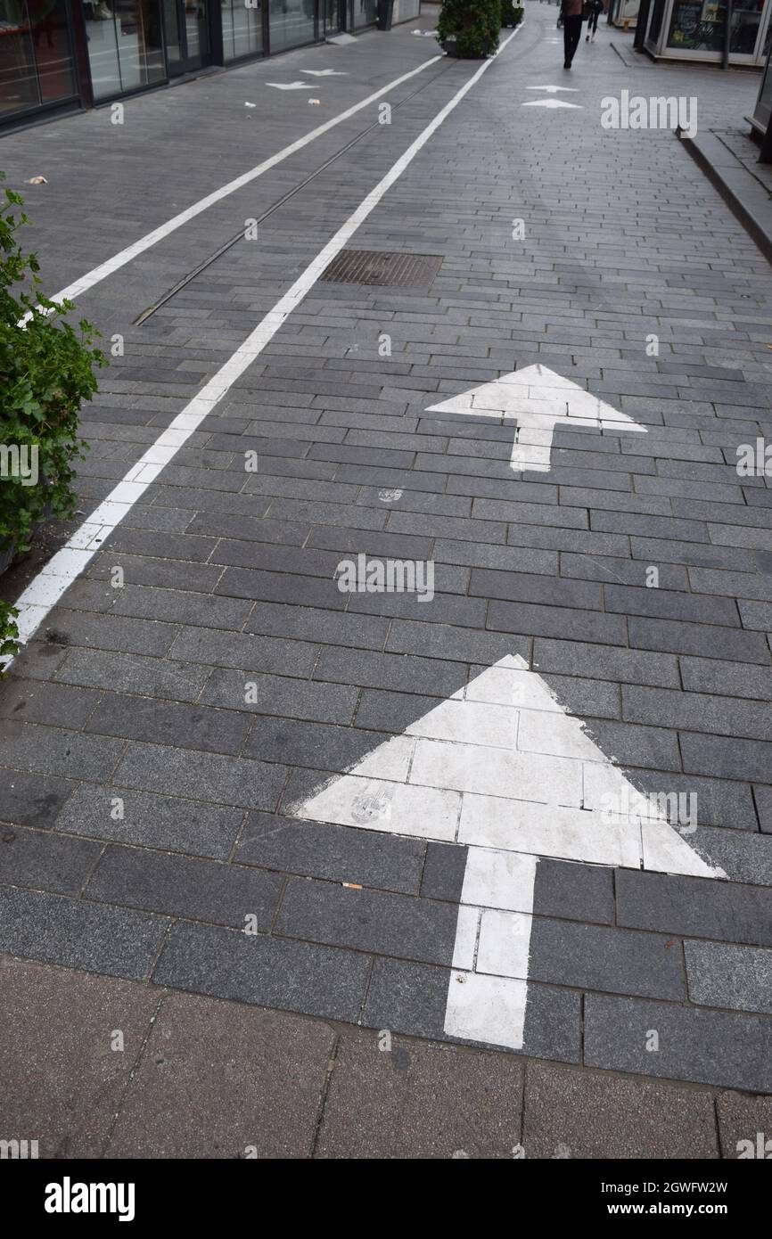 Abgenutzte Pfeile, die die Teilung in die soziale Distanz in einer Einkaufsstraße im Stadtzentrum von Rotterdam zeigen Stockfoto