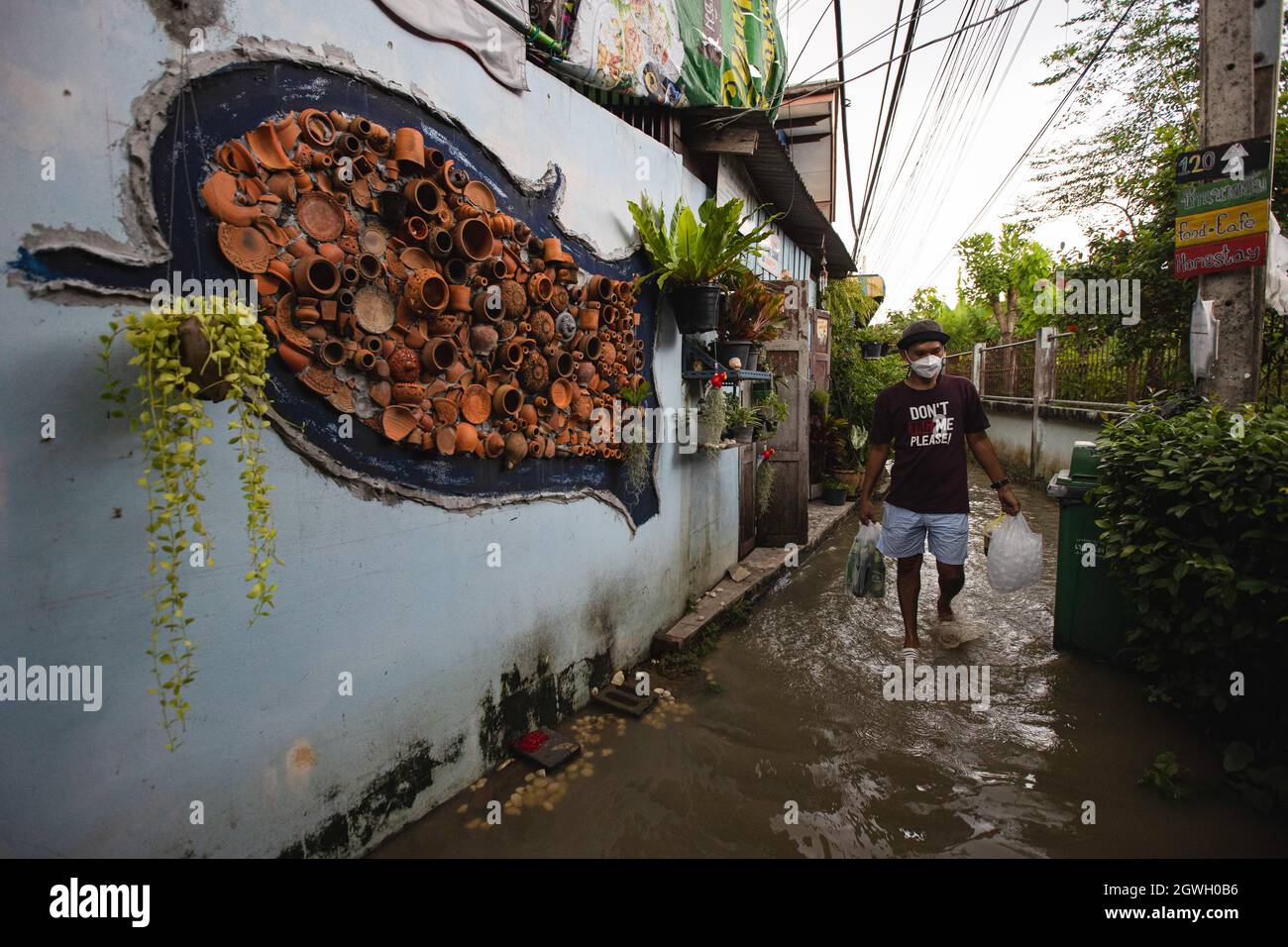 Nonthaburi, Thailand. Oktober 2021. Kor Krets Bewohner spaziert durch eine untergetauchte Gasse. Nach dem Sturm von Dianmu wurden 20 Provinzen betroffen, das Wasser war in die nächste Provinz von Bangkok geflußt worden. Die Gemeinde am Flussufer in Nonthaburi steht vor einer Sturzflut, die sich jeden Tag ändert. Kor Kret (Flussinsel in Nonthaburi) hat jeden Abend einen Anstieg des Wasserpegels und sinkt morgens, je nach Gezeiten. Kredit: SOPA Images Limited/Alamy Live Nachrichten Stockfoto