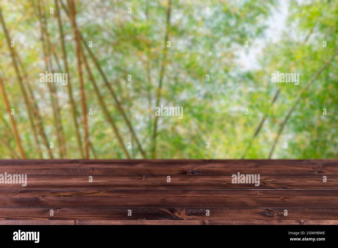 Blur grünen Baum Bambus Hain Wald mit Holzfläche forground für Produkte Montage Werbung Hintergrund. Stockfoto