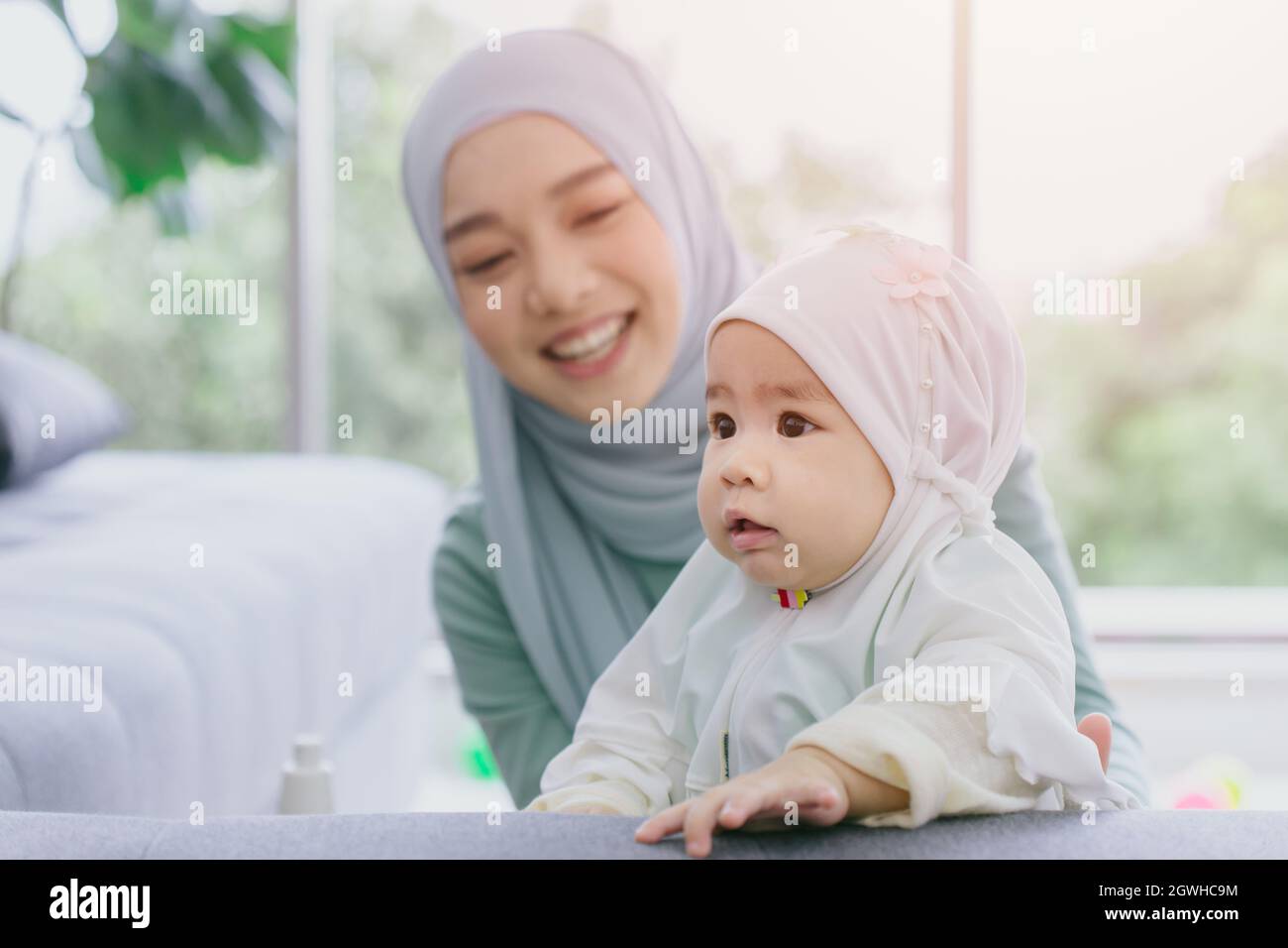 Muslim Mutter Blick auf ihr Baby glücklich lächelnd Kleinkind häusliche Pflege zusammen niedlich schöne Kindheit innen. Stockfoto