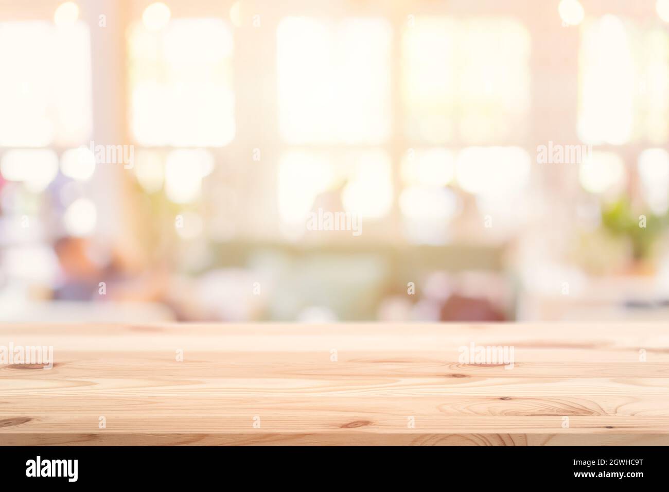Hölzerne Tischplatte Vordergrund mit verschwommenem Indoor Cafe Shop und Restaurant Hintergrund für Produkte Display Montage Werbebanner. Stockfoto