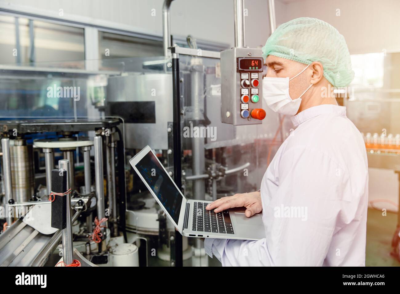 Ingenieur, der mit Laptop in der Lebensmittelfabrik Maschinenproduktion Inspektor mit Hygienekleidung arbeitet. Stockfoto