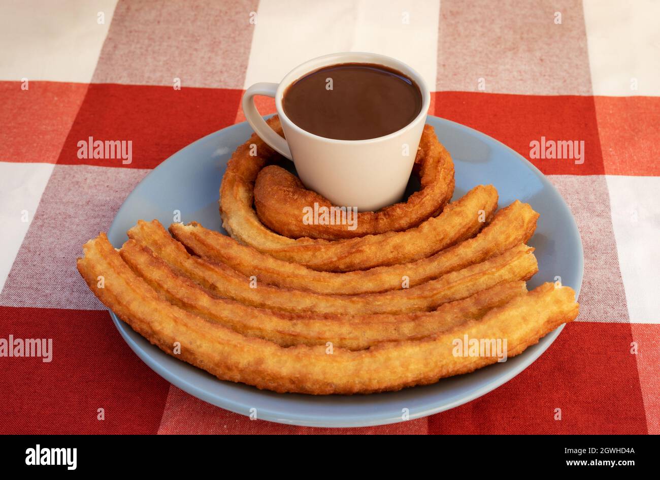 Teller mit einer Tasse Schokolade und Churros rund um die Tasse, Frühstück oder Snack in Andalusien, Spanien. Stockfoto