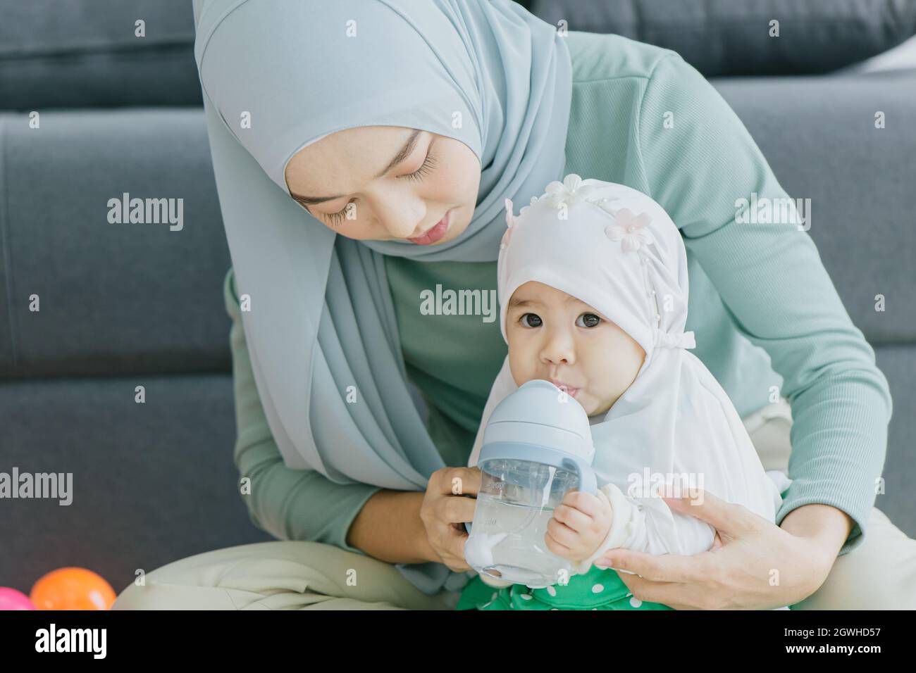 Muslim Mutter schauen kümmern Baby glücklich lächelnd mit Kleinkind zu Hause zusammen niedlich schöne Kindheit innen. Stockfoto