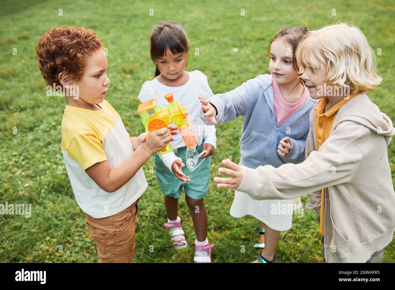 Portrait einer Gruppe von Kindern, die im Park zusammen mit einem Bubble-Spielzeug spielen Stockfoto