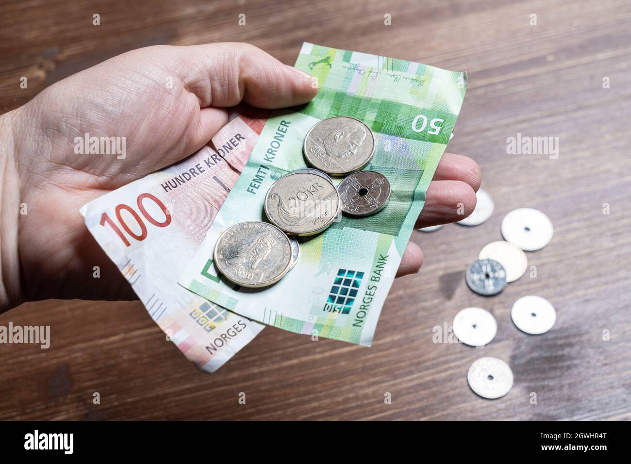Oslo, Norwegen. September 2021. Einige norwegische Kronen-Scheine und Münzen in der Hand Stockfoto