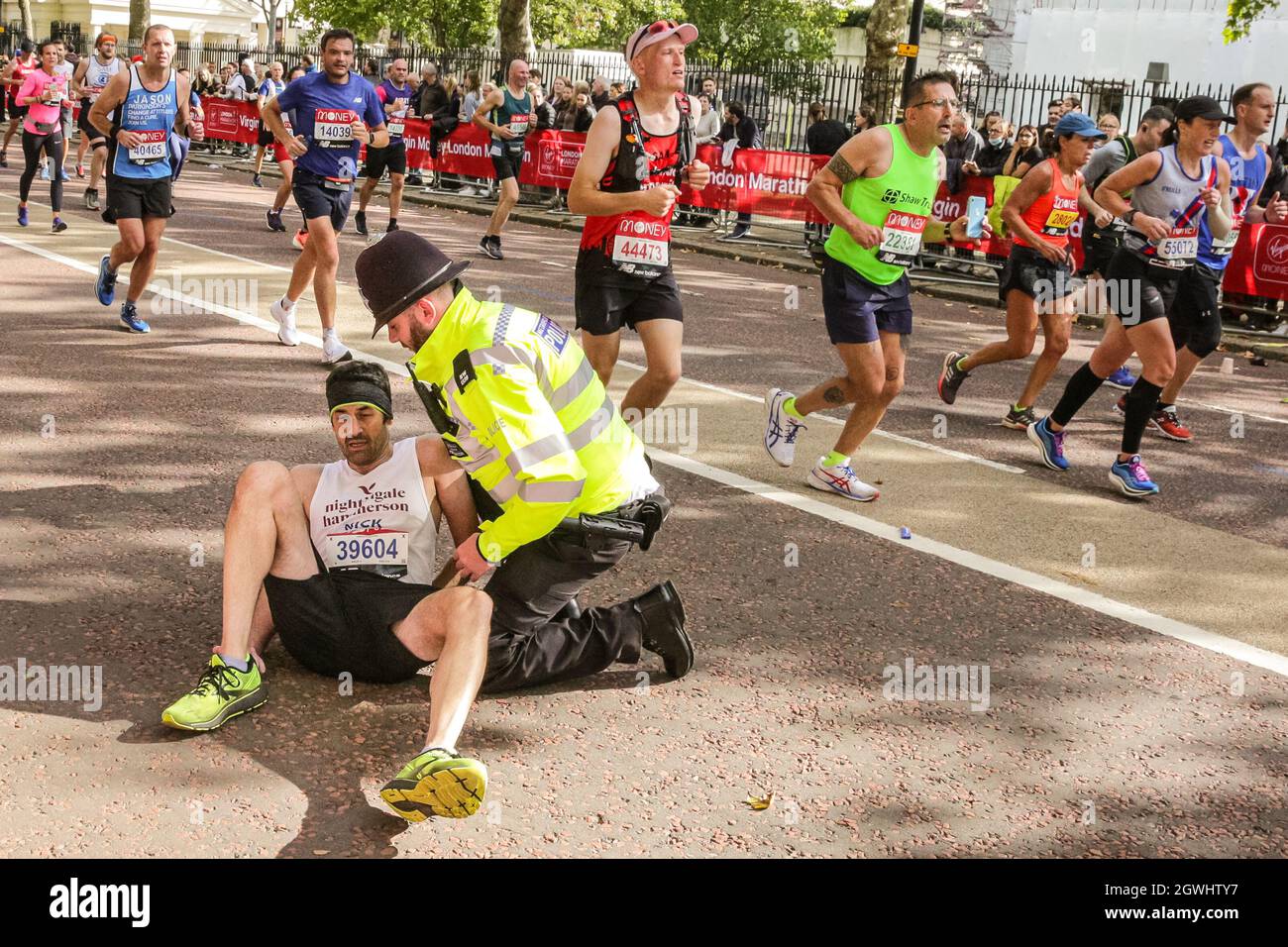 London, Großbritannien. Oktober 2021. Auf der letzten Meile beim Birdcage Walk wird einem eingestürzten Läufer von Polizei und Sanitätern geholfen. Nach einer 2-jährigen Abwesenheit kehrt der Virgin Money London Marathon zu seinem traditionellen Kurs von Blackheath zur Mall zurück. Mit über 40,000 Teilnehmern und einer ähnlichen Zahl, die gleichzeitig den virtuellen Marathon auf einer Strecke ihrer Wahl absolvieren wird es der größte Marathon überhaupt sein. Kredit: Imageplotter/Alamy Live Nachrichten Stockfoto